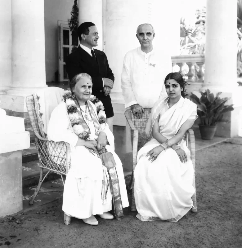 A black and white group photo of Dr. Maria Montessori sitting on the left and Rukmini Devi sitting on the right with Mario Montessori on the left and Arundale standing on the right shot in 1940 in Adyar